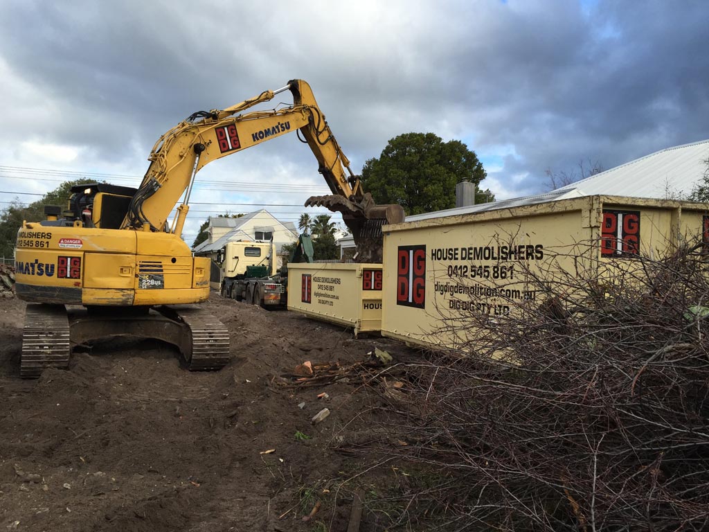 DigDig Demolition excavator and skip bin on site beside a partially demolished weatherboard house