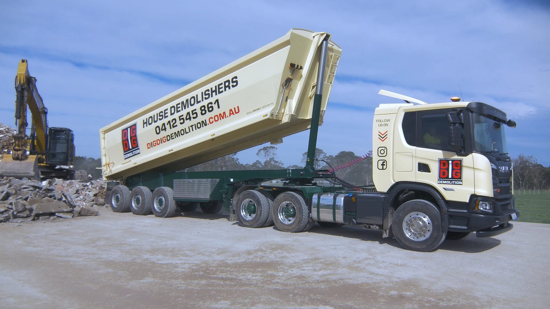 DigDig Demolition tipper truck unloading recovered rubble on site beside an excavator